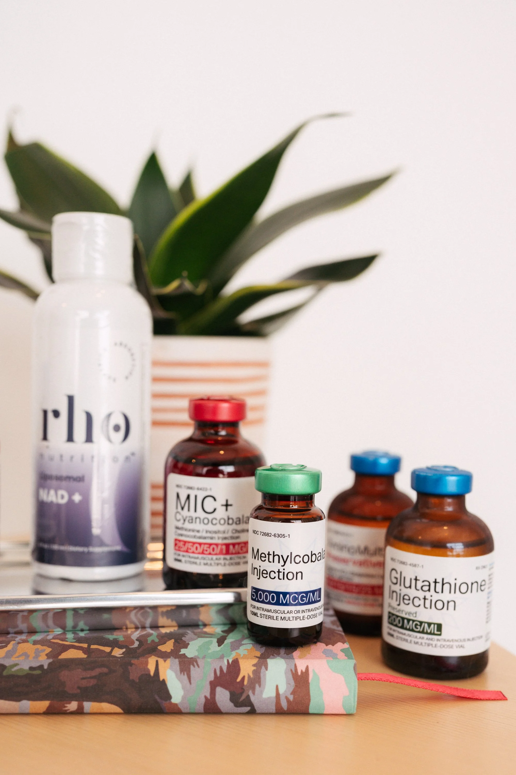 Several medical bottles labeled with medications, placed on a desk with a decorative box and a potted plant in the background.