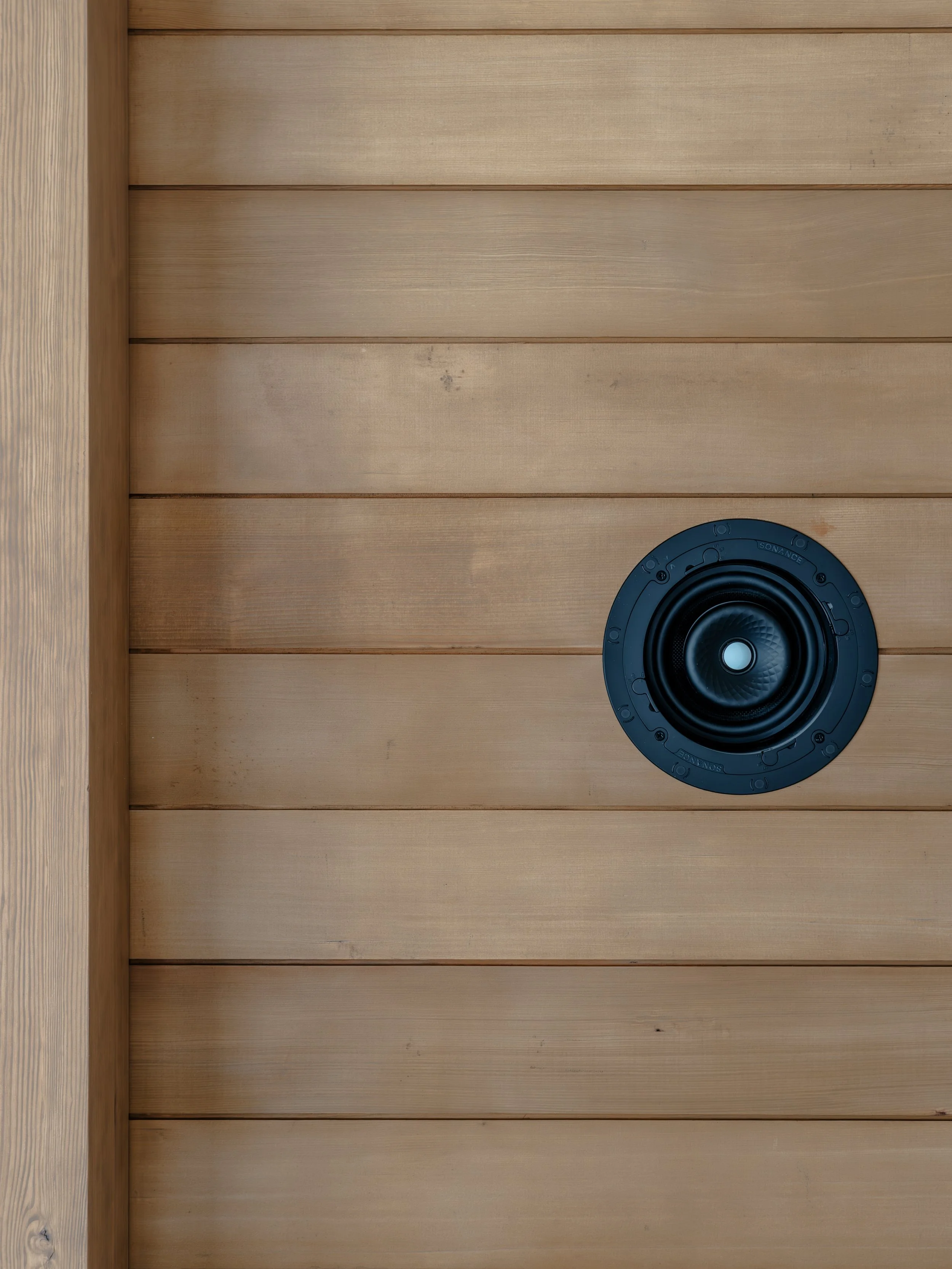 Wood-paneled ceiling with a black round speaker or ventilation cover positioned toward the bottom right.