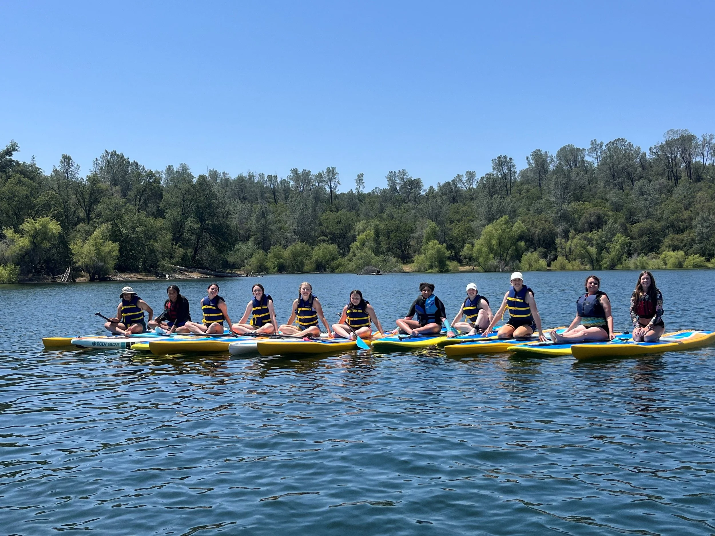 girls on lake on paddleboards with lifejackets