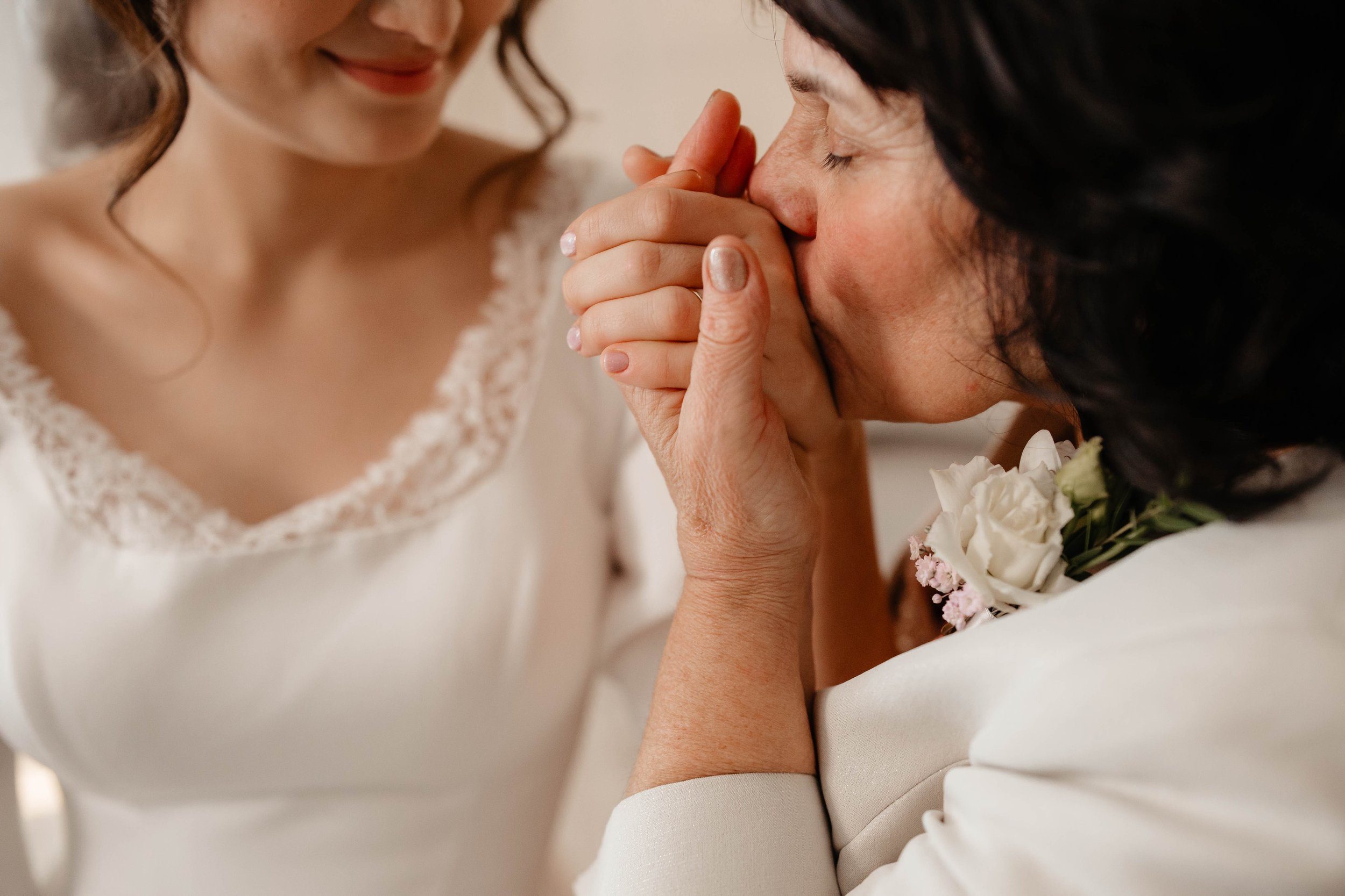 An emotional moment between a bride and groom as the groom kisses the bride's hand during their wedding ceremony.
