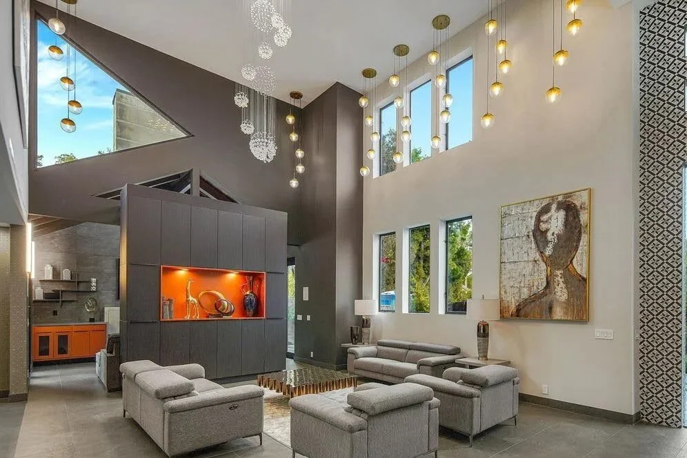 Contemporary living room featuring an 11‑foot gray central storage unit, a copper cantral decorative space, large windows, and modern pendant lights