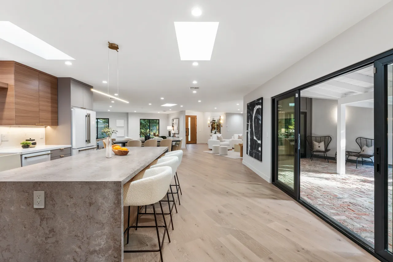 Modern kitchen island with gray cabinetry, stone waterfalls ends and seating.