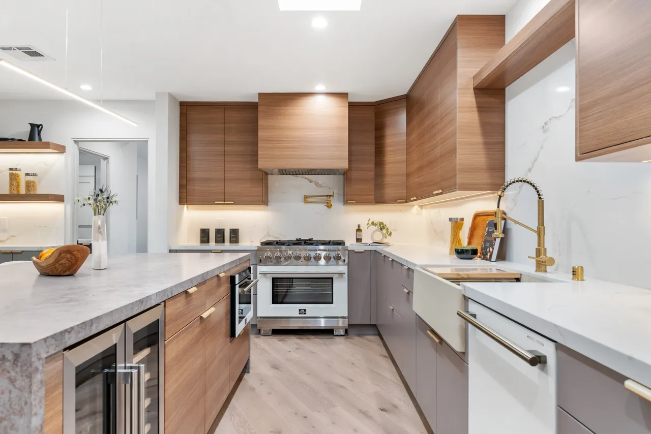 Professional range and hood area with horizontal wood‑grain upper cabinets and clean gray base cabinetry.