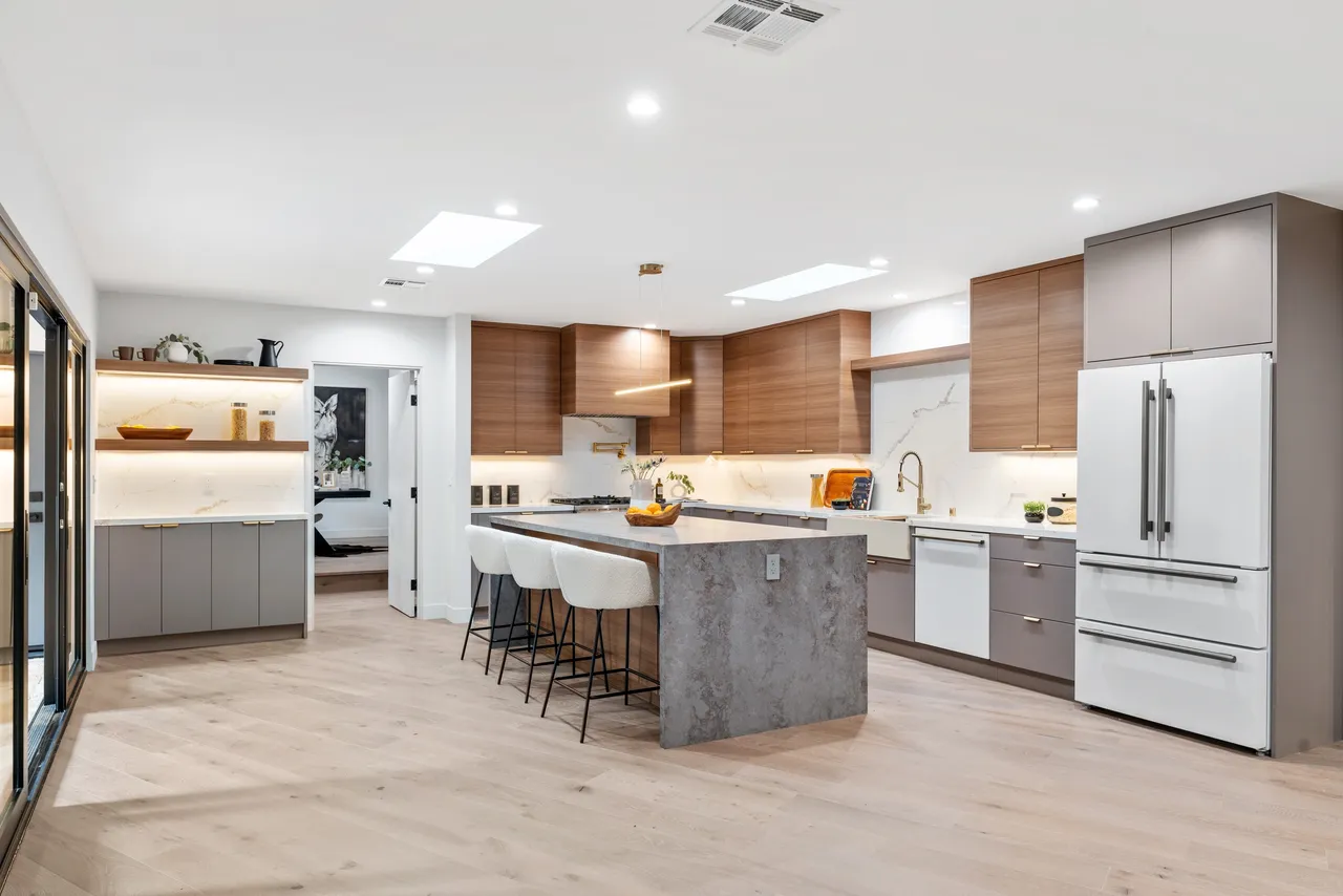 Angled view of modern Los Angeles kitchen showcasing wood‑grain cabinetry, gray uppers, and open layout