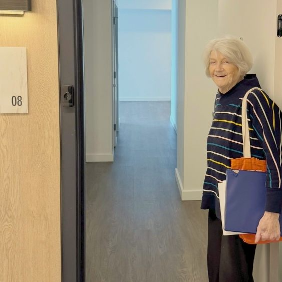 Smiling senior aged woman standing in doorway of new apartment