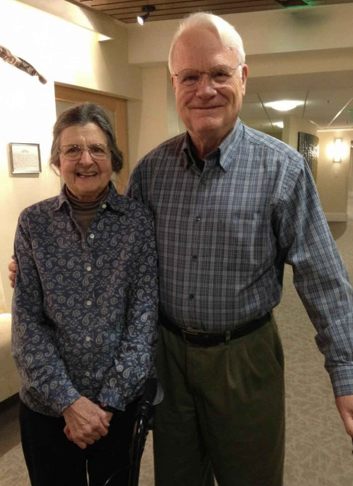 A senior woman and mad standing next to each other with smiles on their faces.