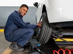 A man changing a tire on a car at a repair shop.