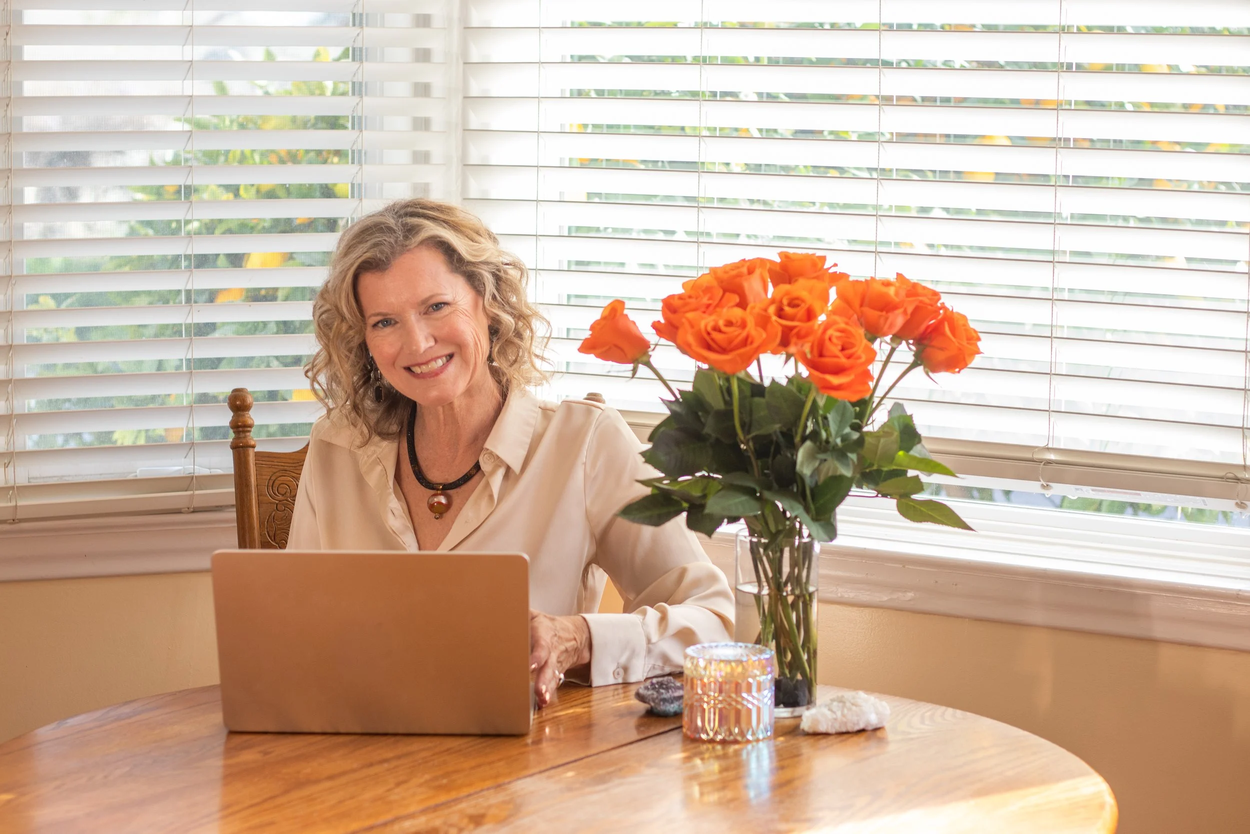 intuitive healer and emotional life coach working at home with flowers and laptop