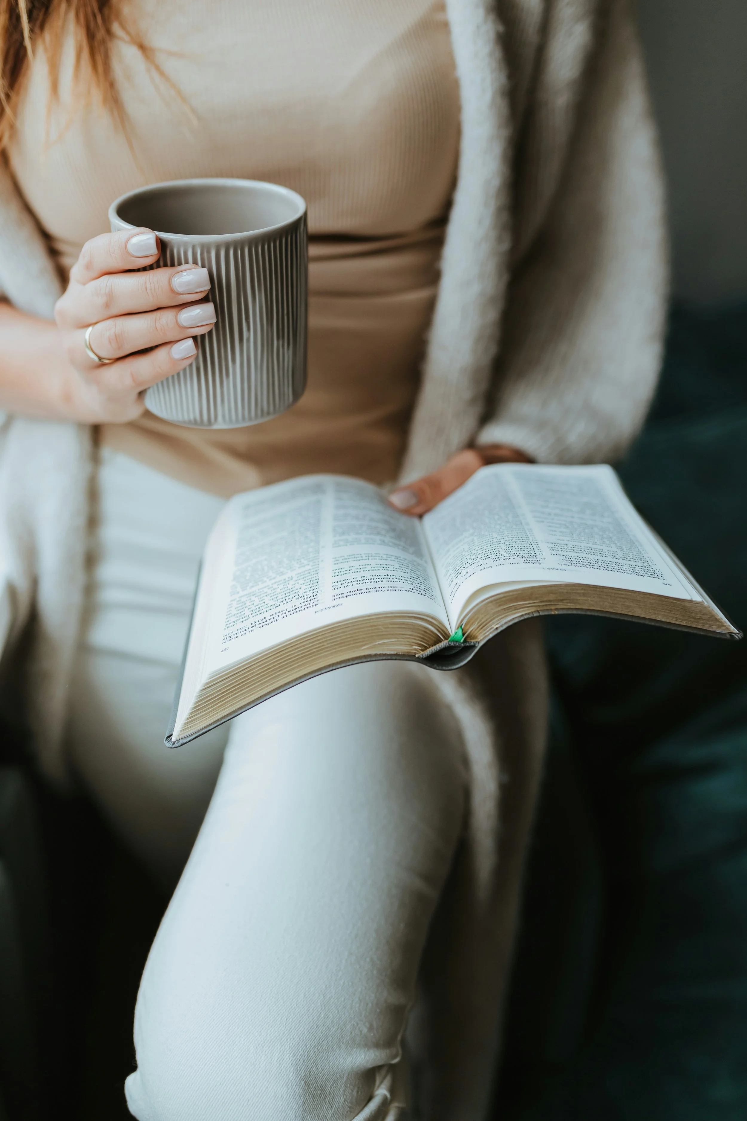 woman holding coffee and reading book in a calm, reflective moment