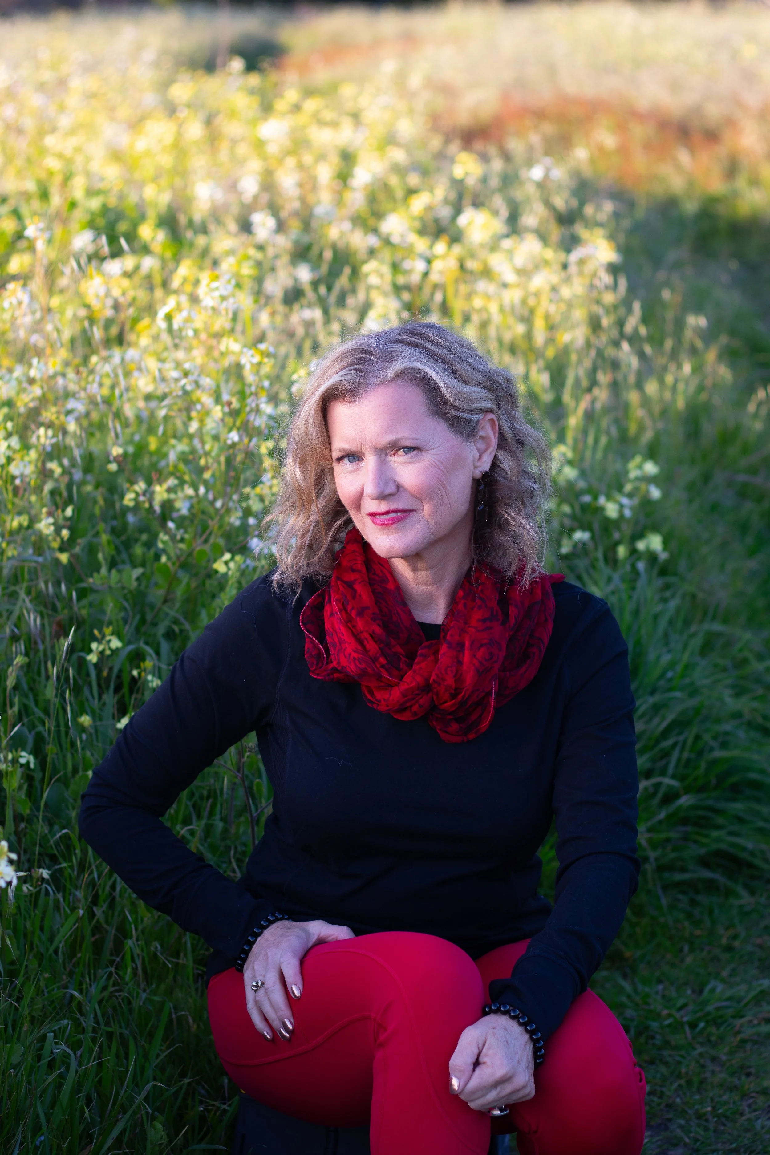 Kimberly Katherine sitting in a field, representing calm, grounding, and personal healing and transformative journey