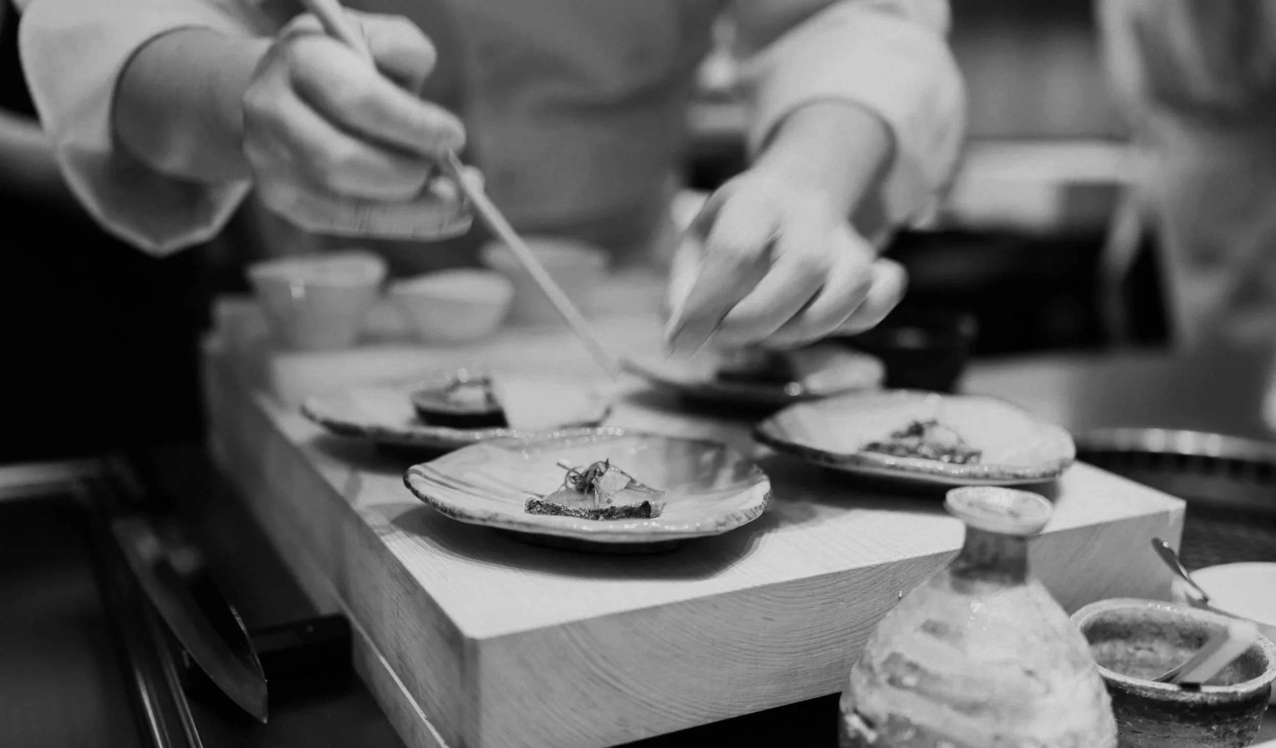 Chef garnishing small seafood dishes in a professional kitchen