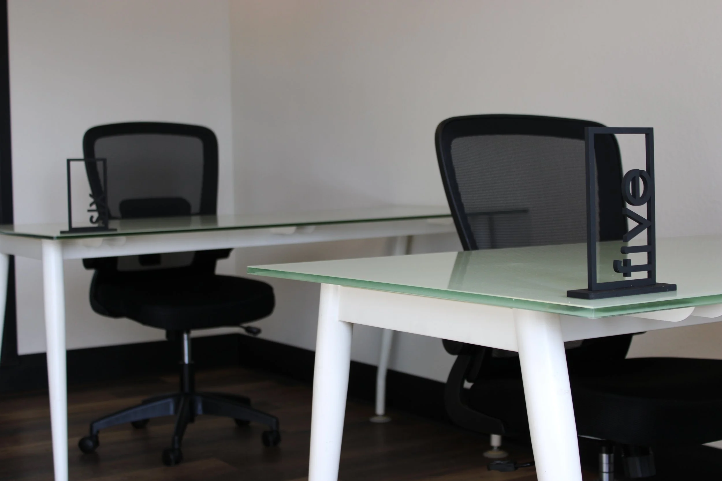 Modern office with glass desks, black ergonomic chairs, and decorative geometric sculptures