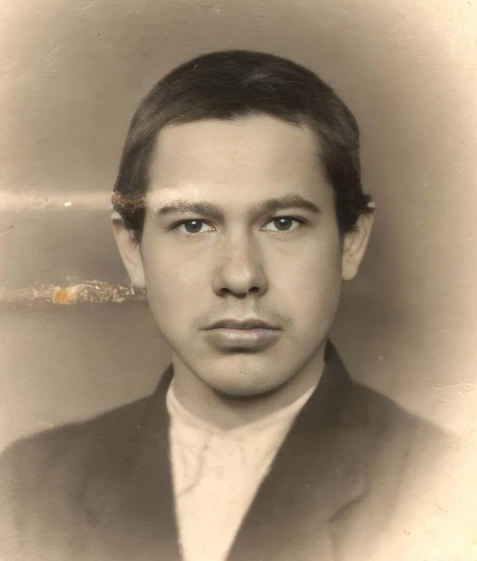 A black and white portrait of a man with short dark hair, wearing a suit jacket and shirt, looking directly at the camera.