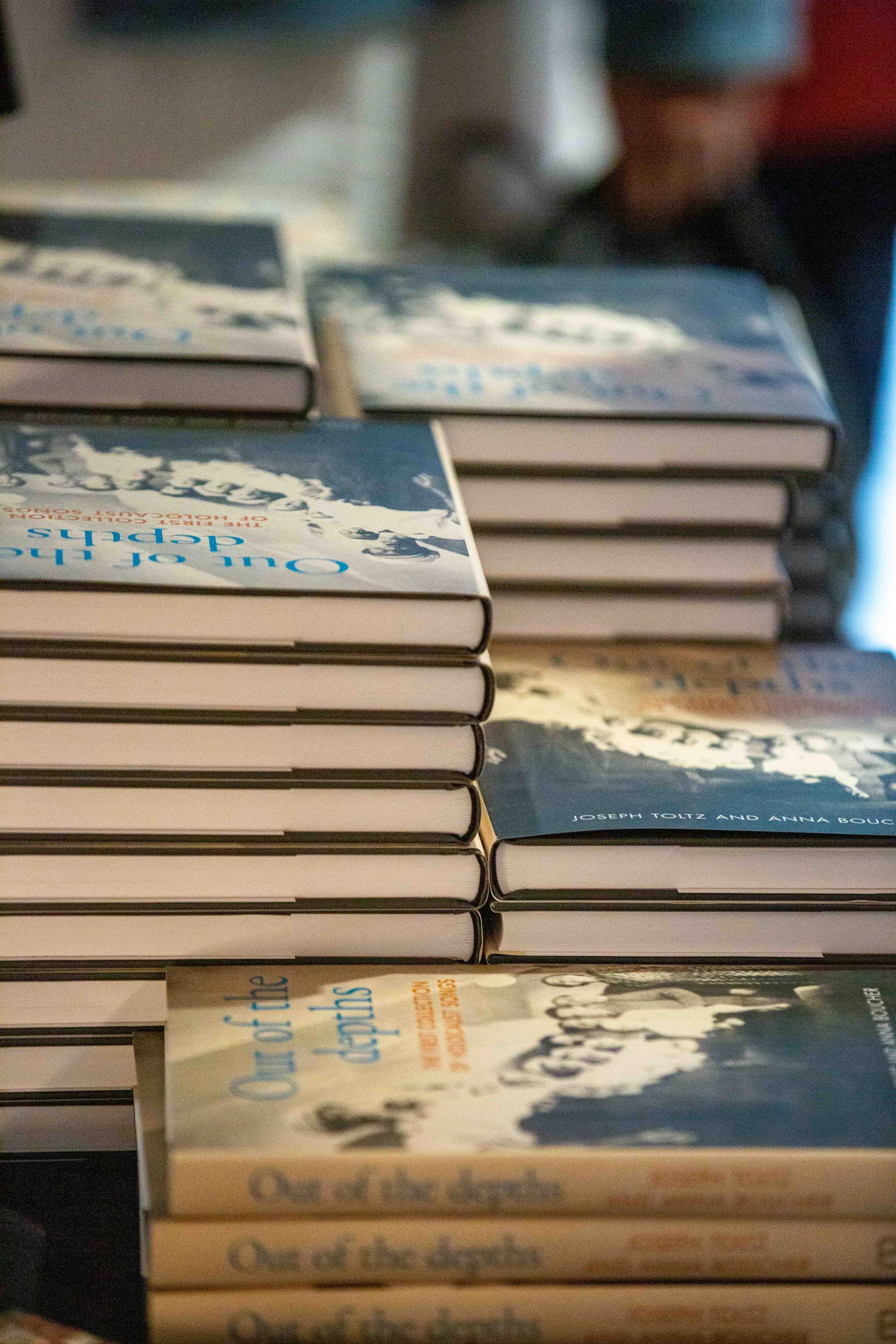 A close-up of a stack of books with the top book titled 'Oceans of Dolphins' by Joseph Toltz and Anna Bouc. The books are stacked horizontally on a surface.