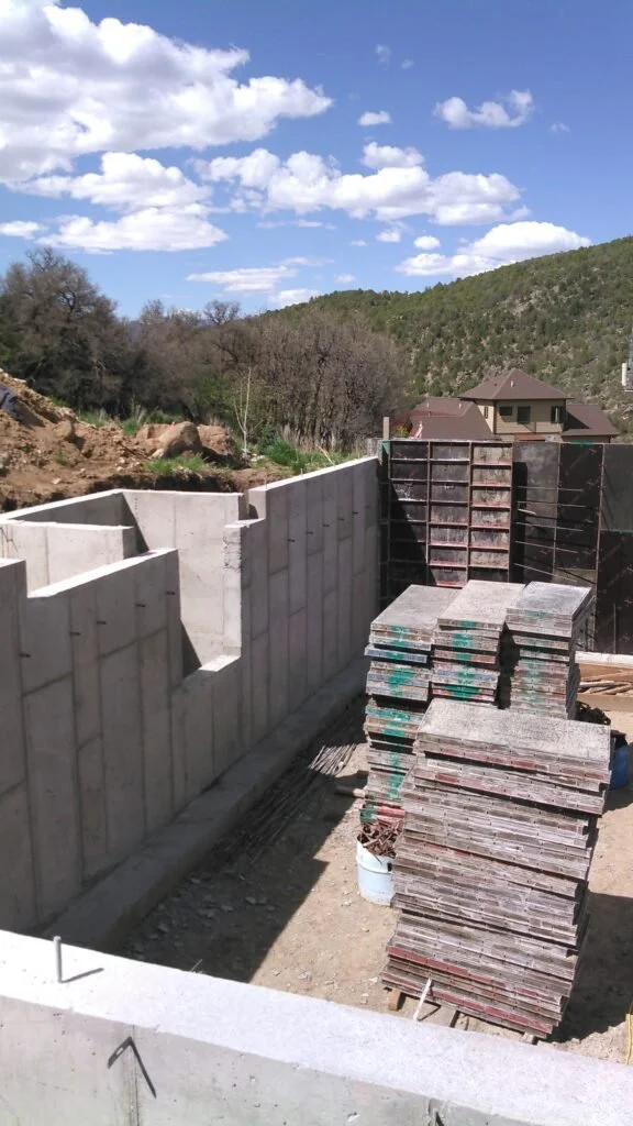 Construction site with concrete wall foundation, stacked concrete paving stones.
