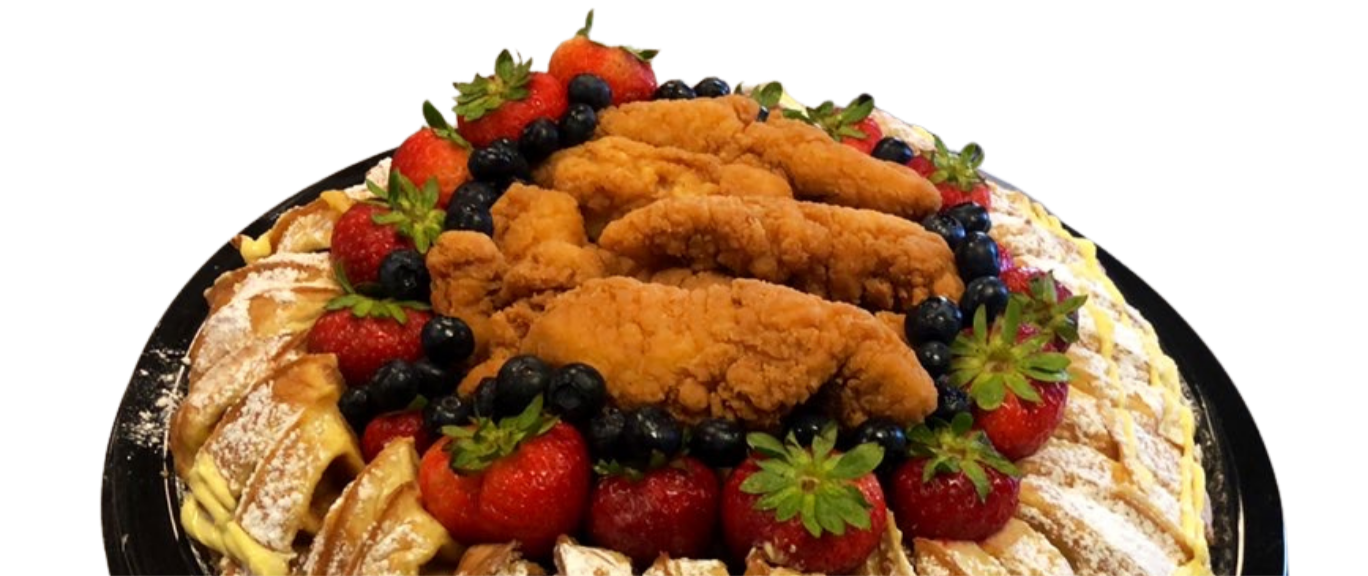 A large platter of fried chicken tenders, surrounded by fresh strawberries, blueberries, and decorative green leaves.