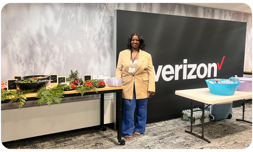 Boomer standing in front of a Verizon logo at a corporate event.