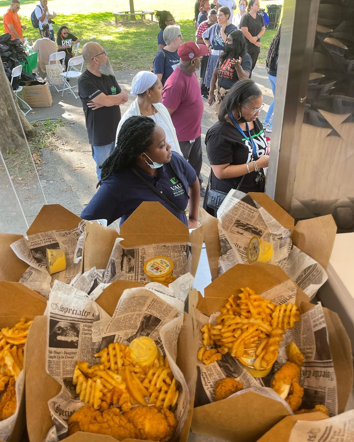 A group of diverse people standing in line outside of Boomer's Food Truck