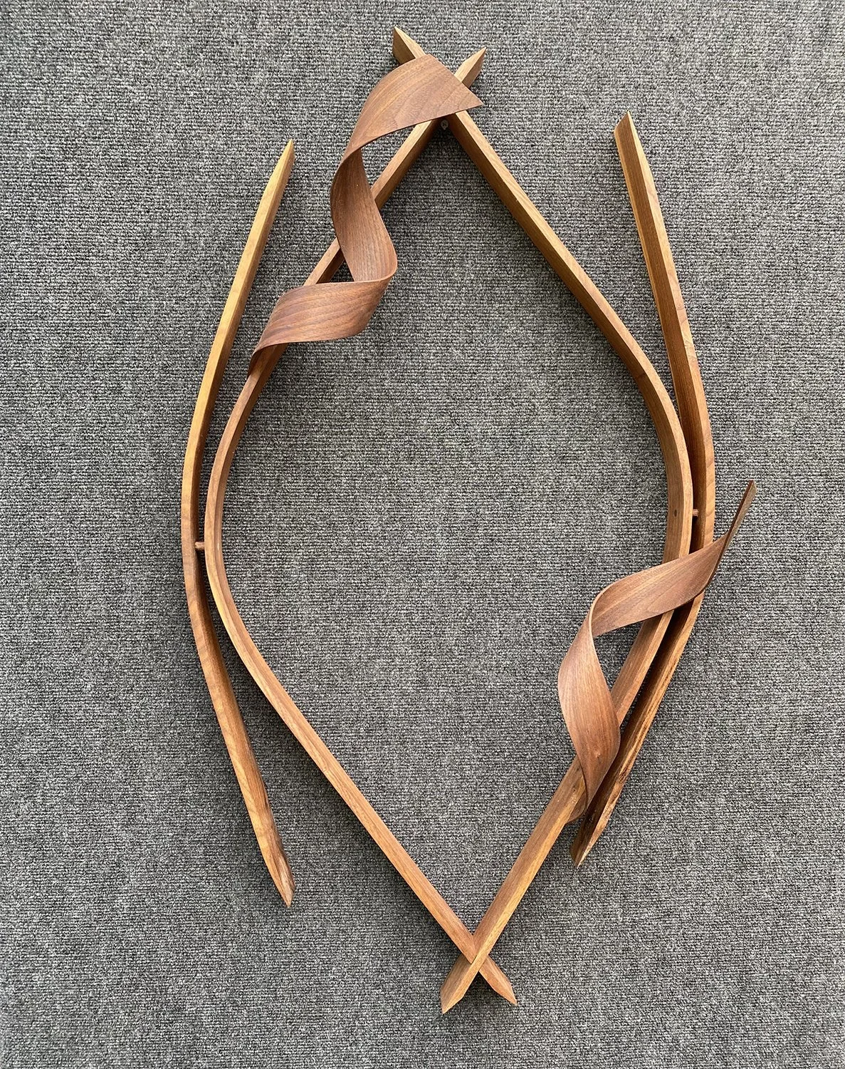 Wooden decor piece shaped like a heart with twisting and pointed details on a gray textured background.