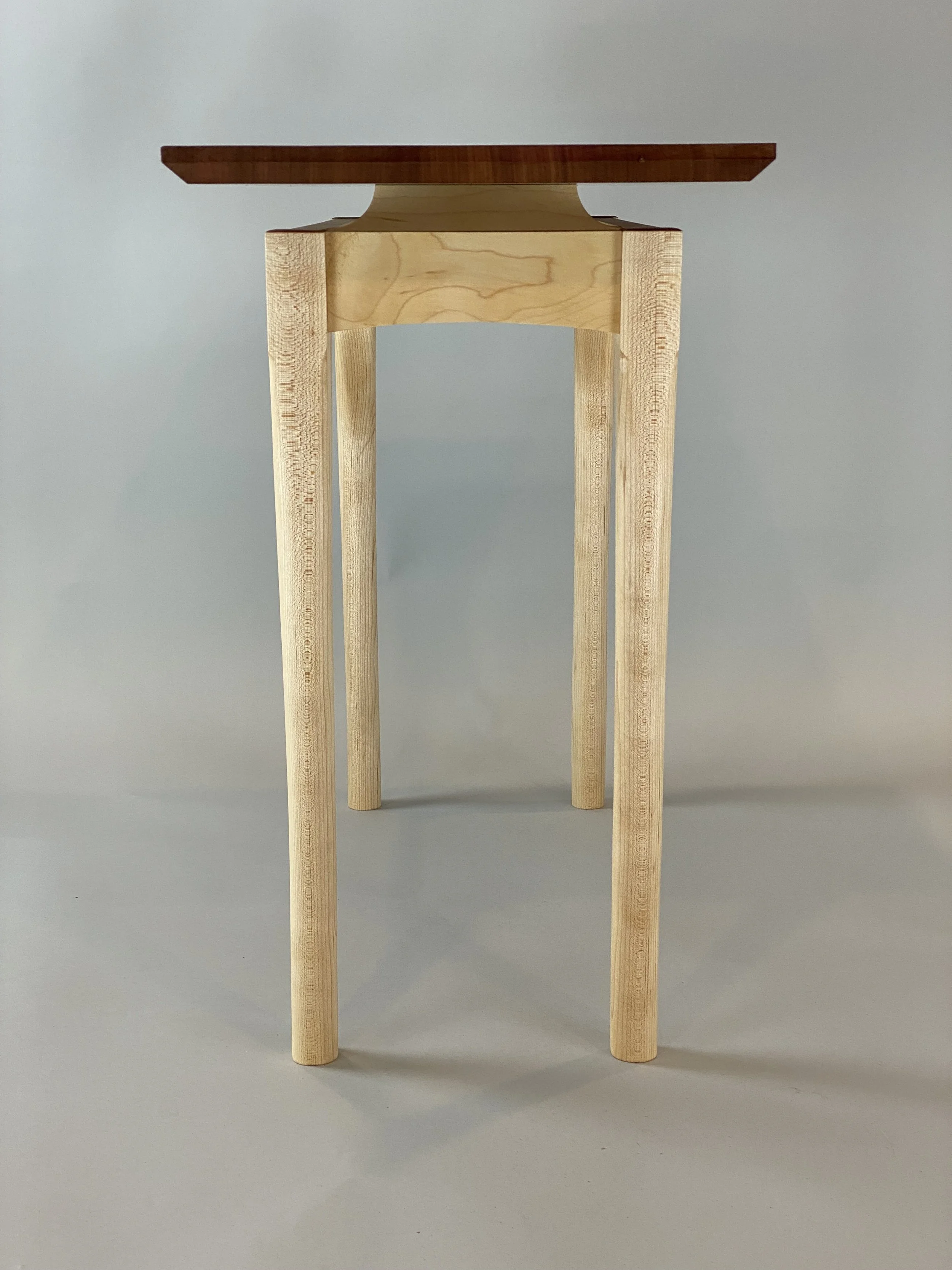 A wooden stool with four legs and a dark brown rectangular seat against a light gray background.