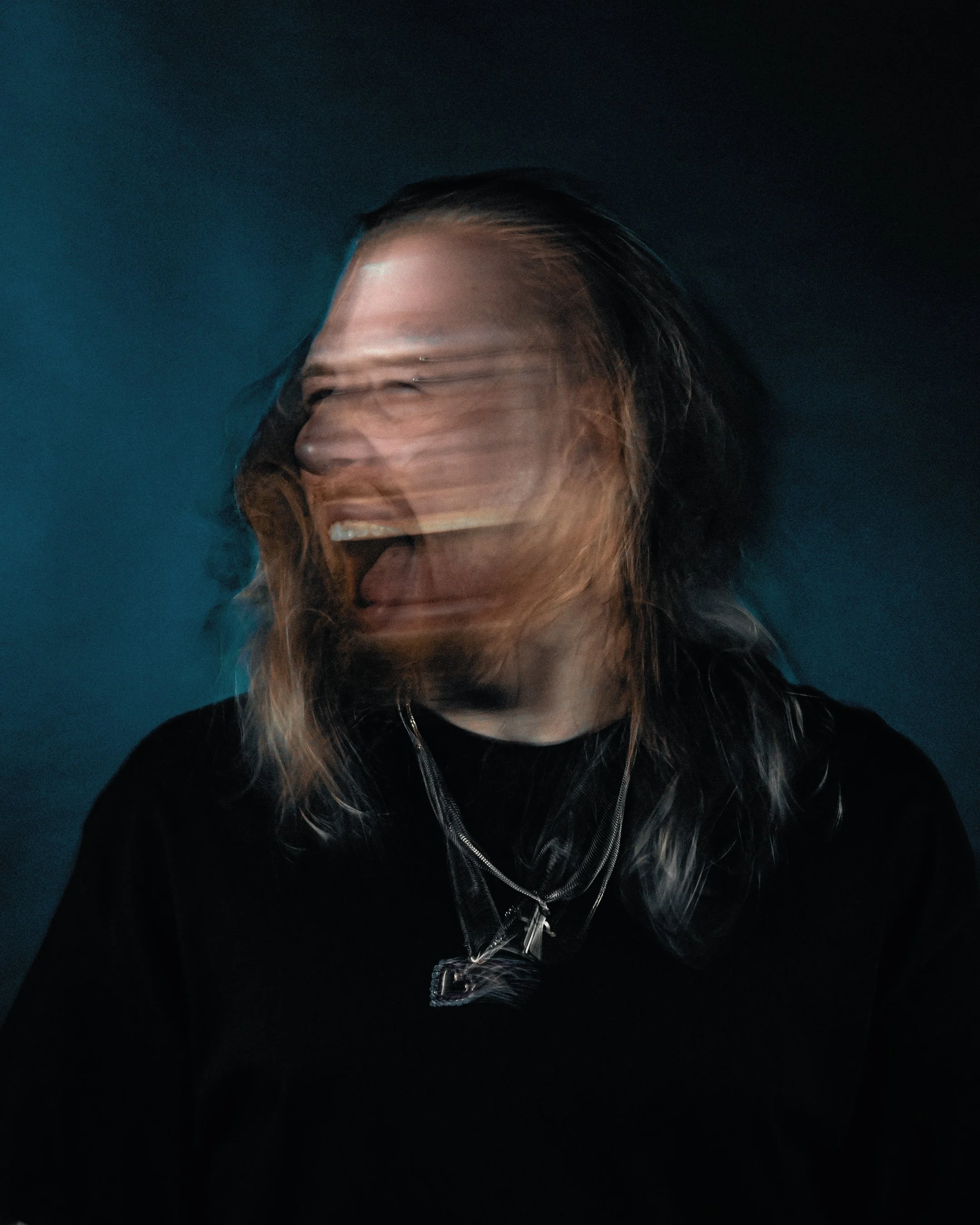 Close-up of a woman's face with a distorted, swirling effect, showing her smile, long hair, and wearing a black jacket with a zipper.