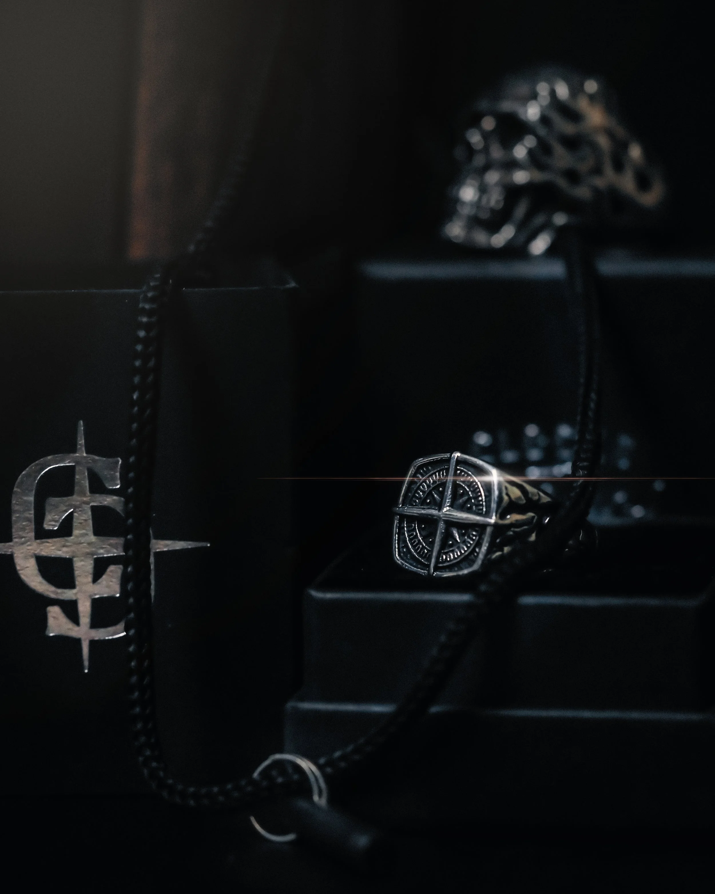 A white lampshade on a standing lamp, with potted plants around it on a dark wooden surface, and a gray wall background.