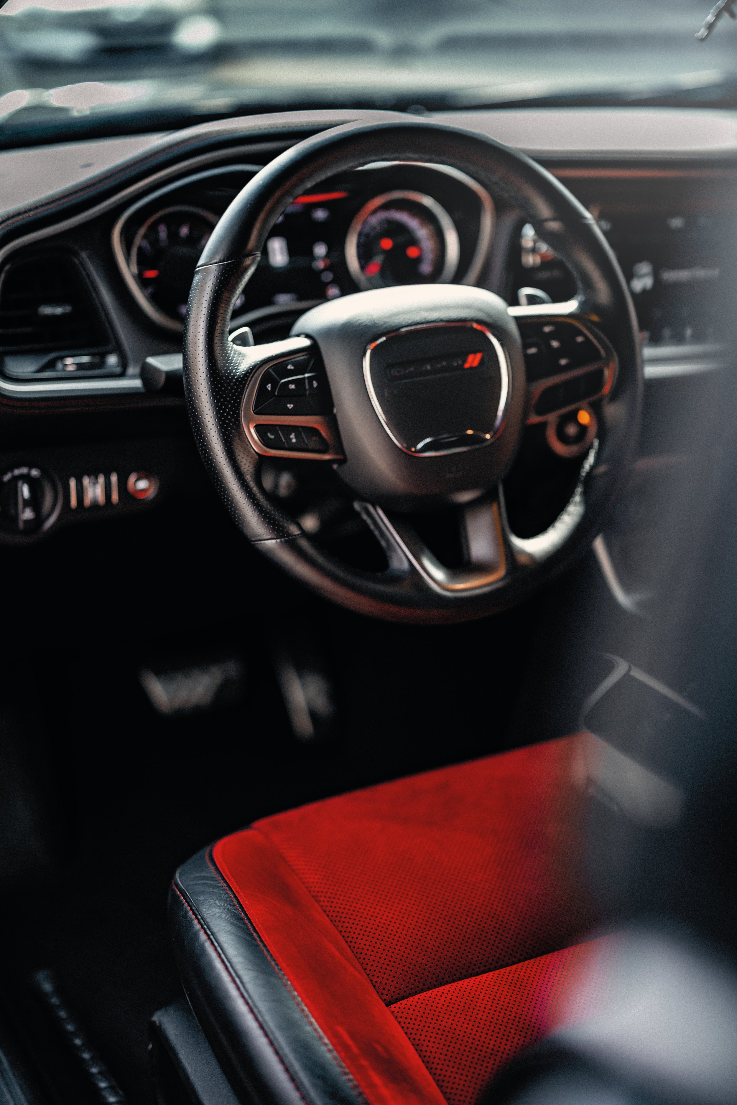 Close-up of red and black car seat and steering wheel interior of a vehicle.