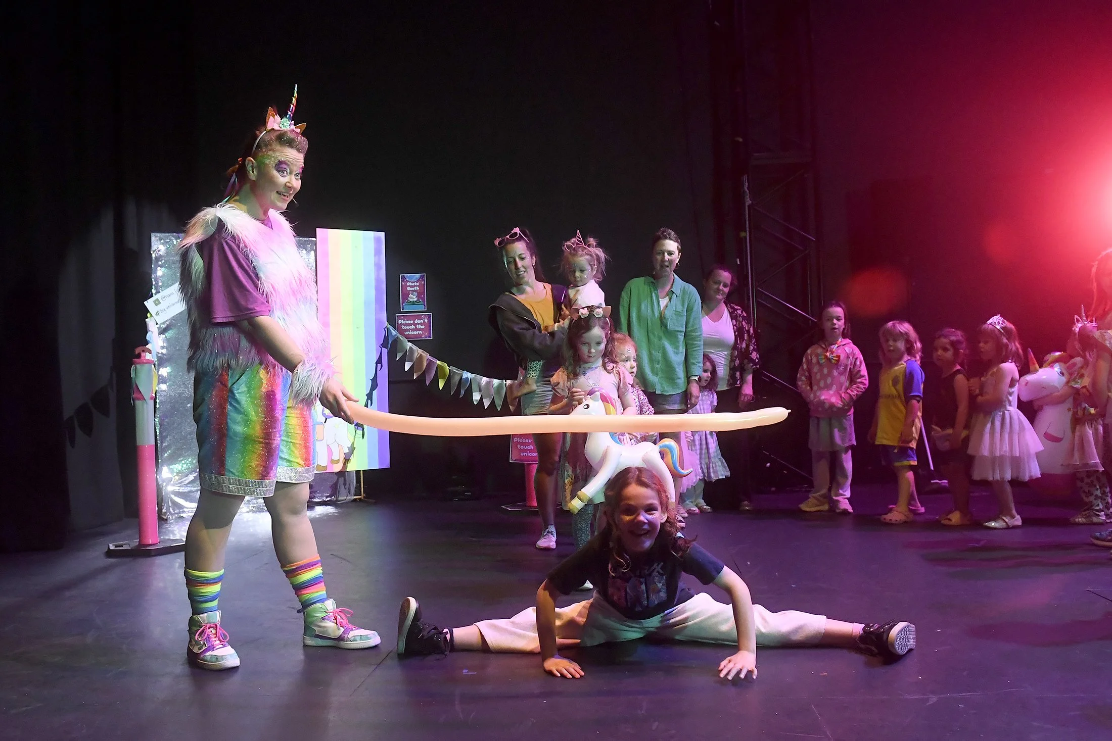 Melbourne birthday party entertainer Hana Fiesta holds a limbo stick for a child to go under at Big Unicorn Dance Party