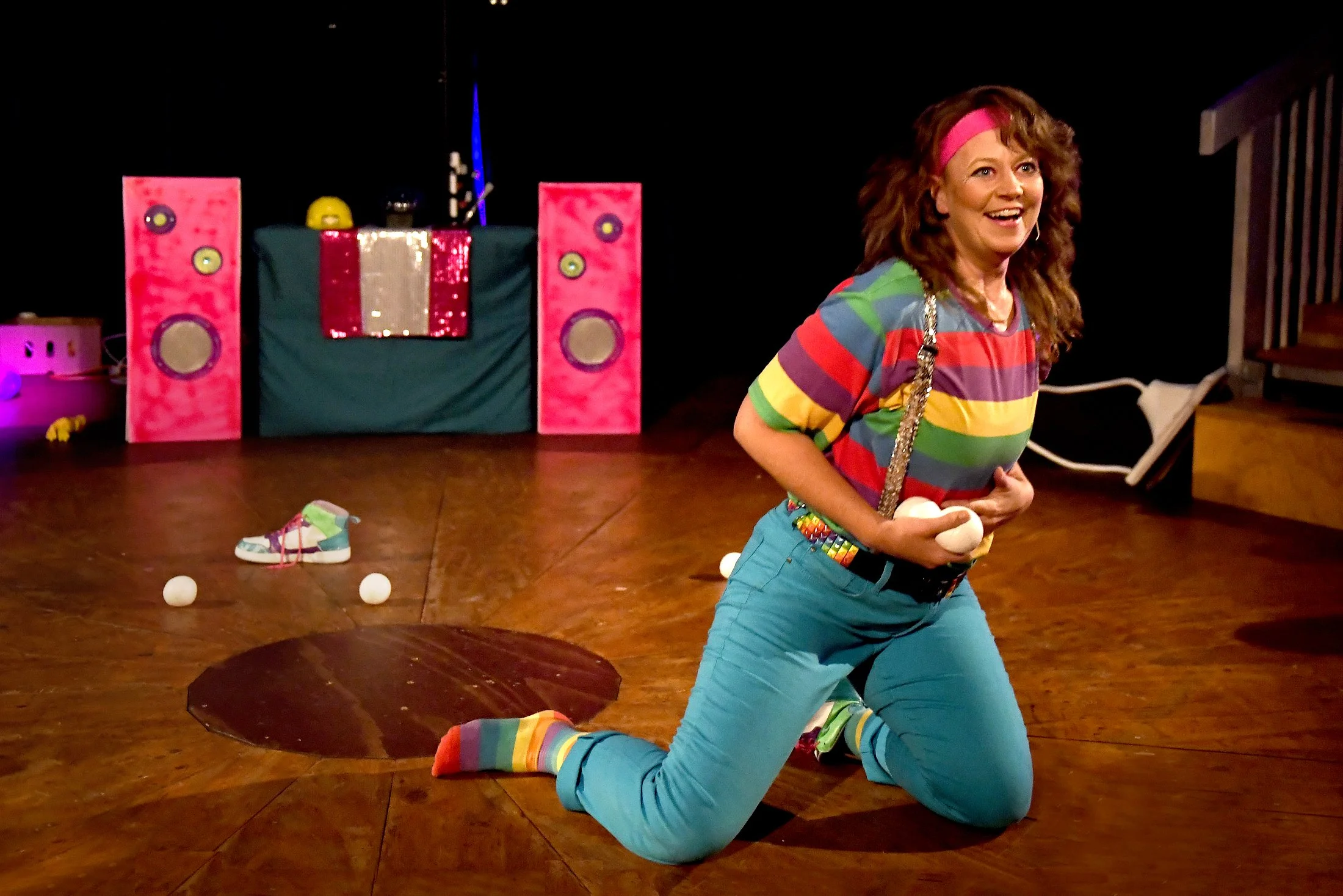 Melbourne performer Hana Fiesta playing the clown kneeling on the stage holding juggling balls