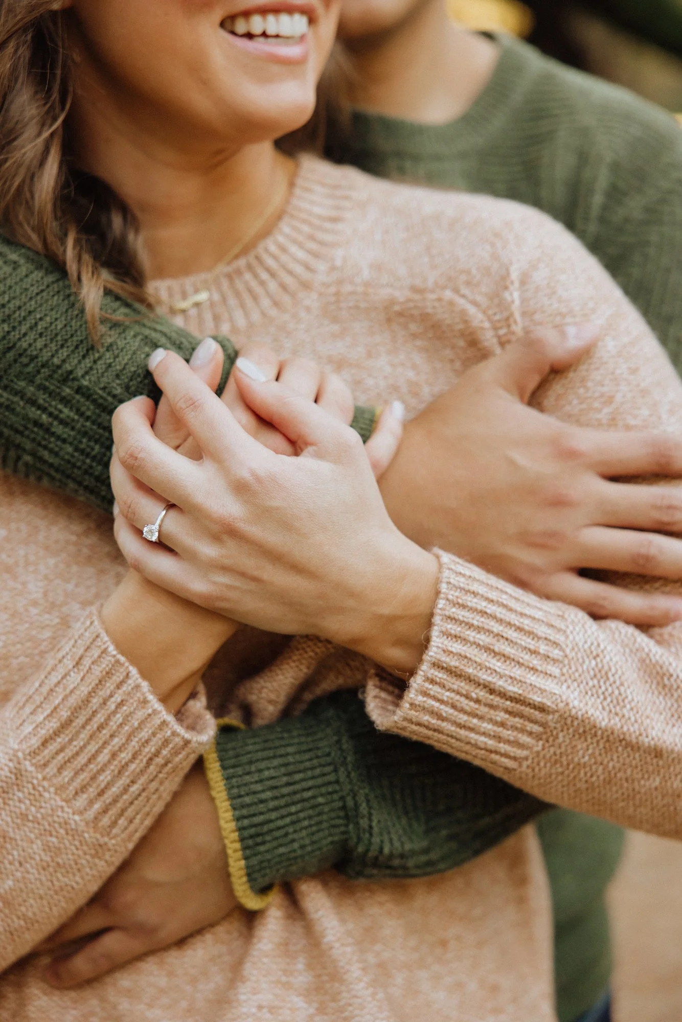 Close-up of a woman smiling and holding a child, with hands placed over their chest, in an affectionate gesture.