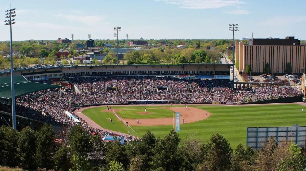A baseball stadium filled with spectators during a game, with players on the field and tall light poles around the stadium.
