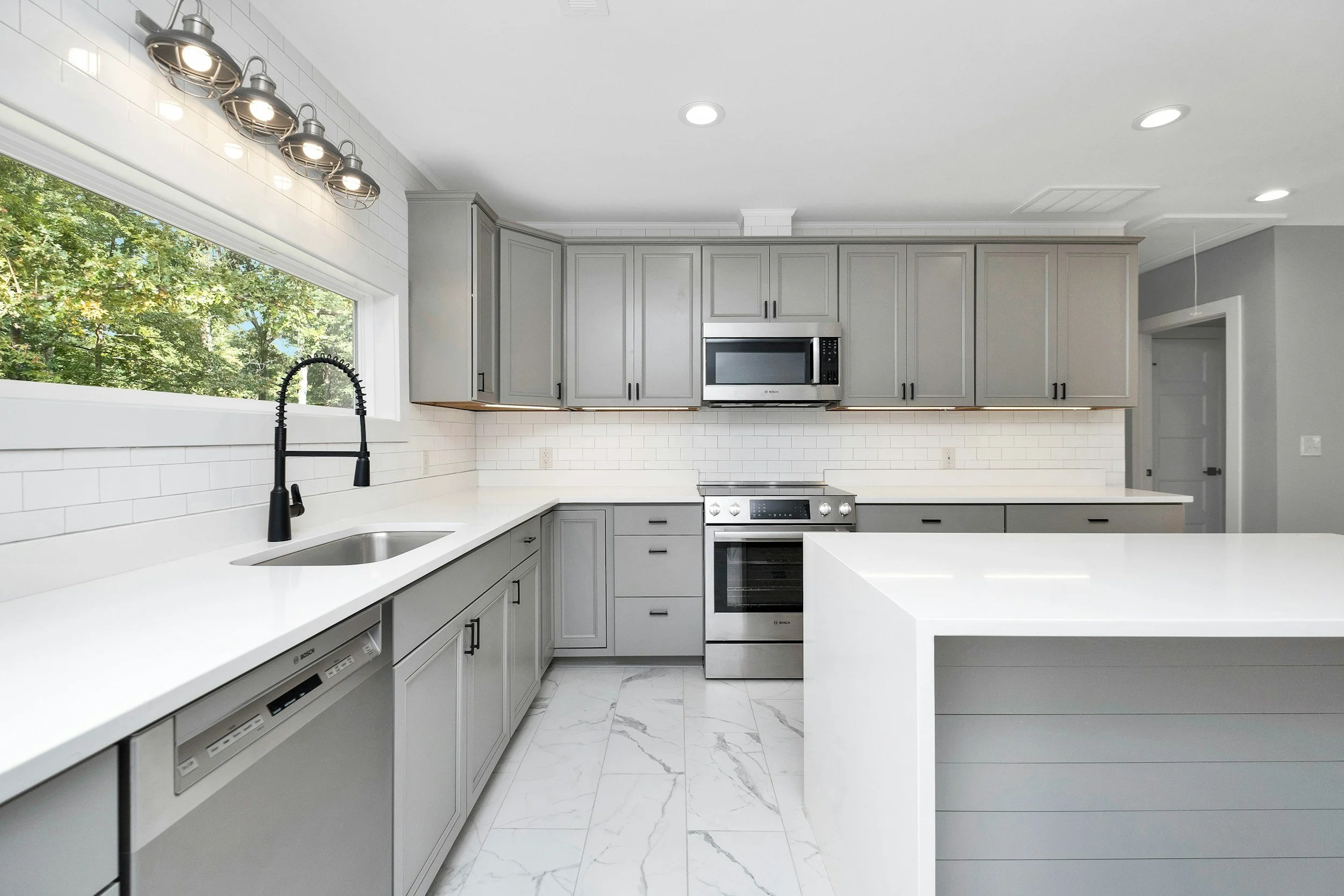 Gray shaker kitchen cabinets with white quartz countertops, center island, and modern finishes.