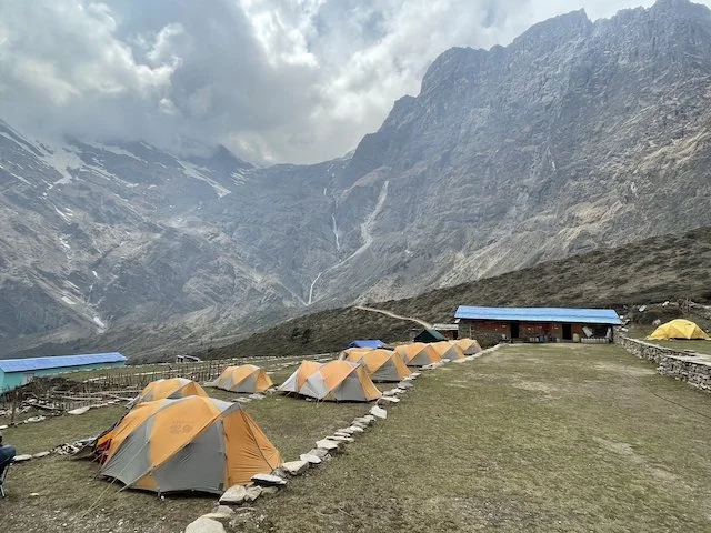 a row of tents at Italian Base Camp near Dhaulagiri with mountains in background and cloudy sky