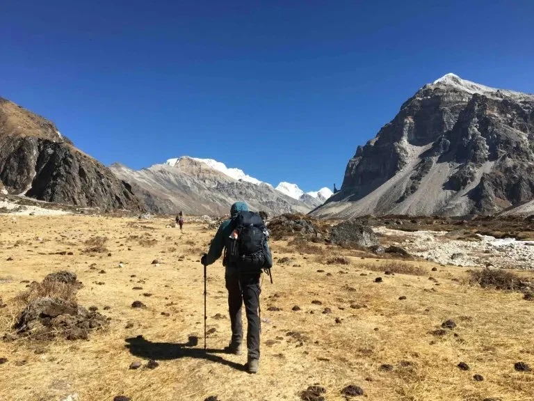 Trekking to North Base Camp along flat grassy land with mountains either side
