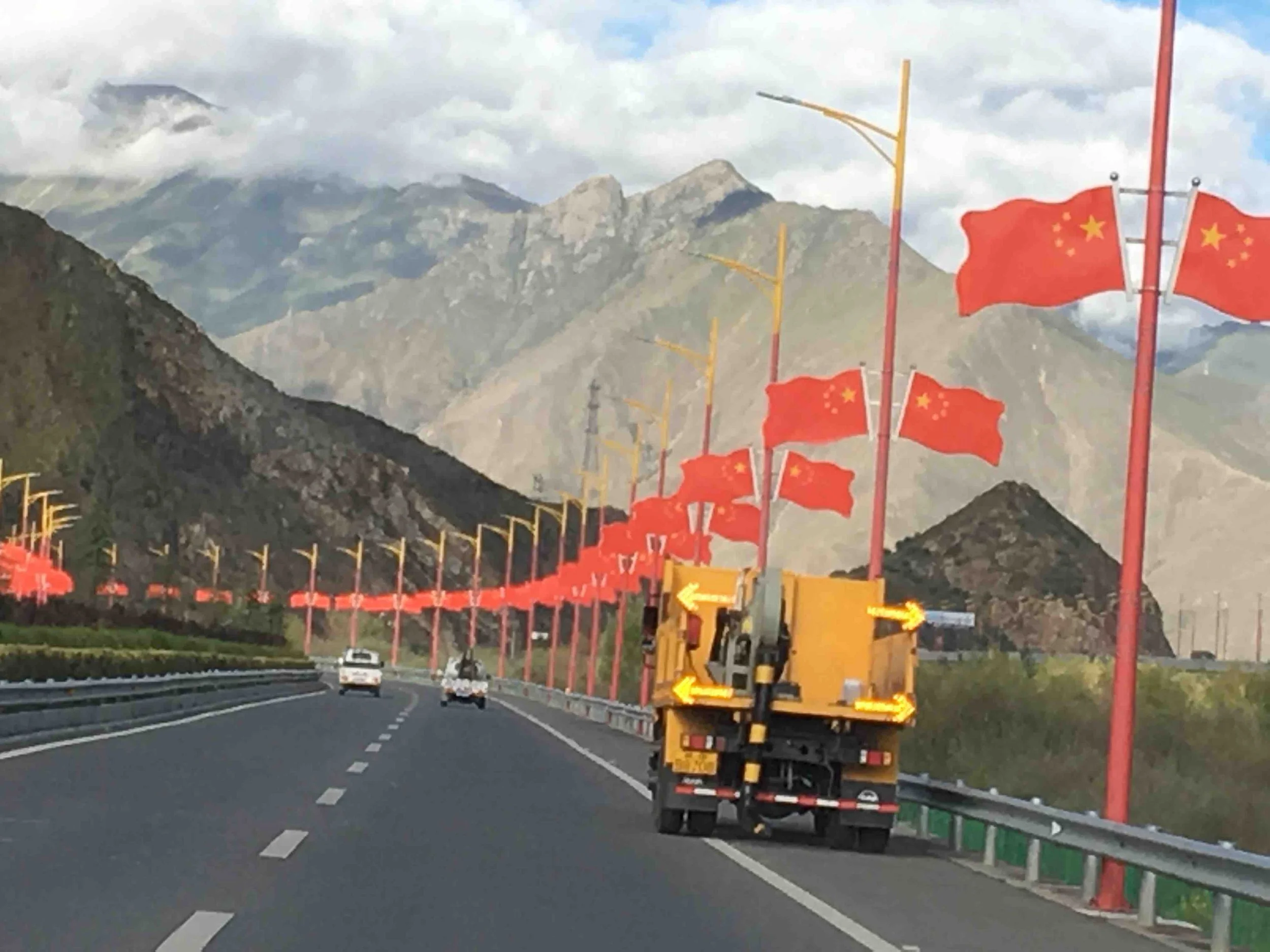 Road out of Lhasa lined with Chinese flags and with mountains ahead