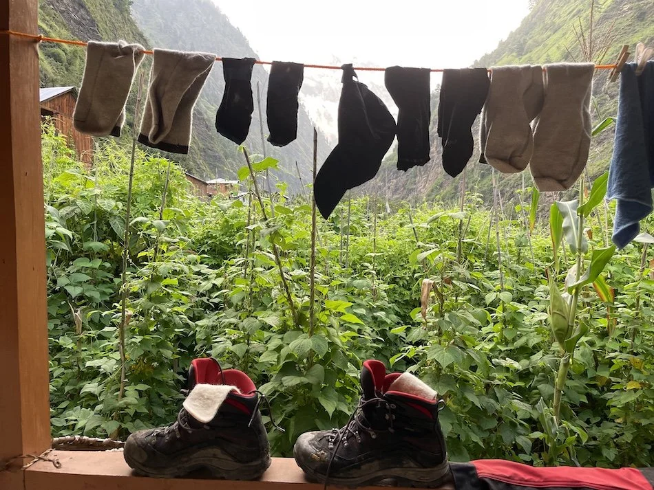 trekkng boots drying in the sun amd a washing line with trekking socks and cap