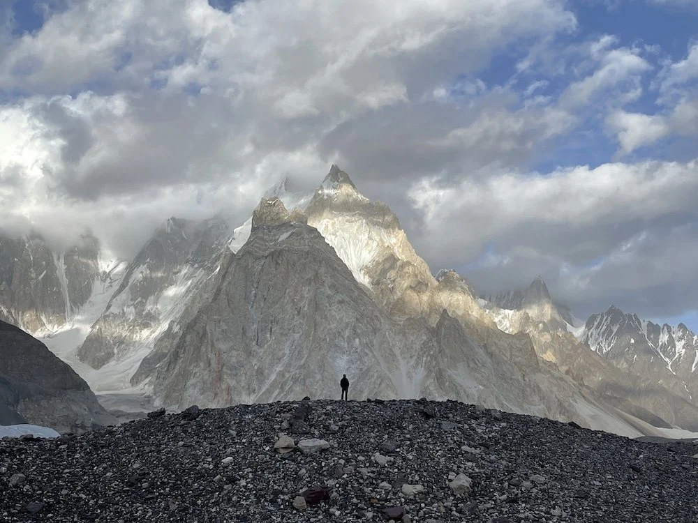 lone trekker standing in front of a sheer mountain wall