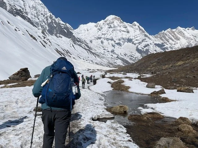 trekkers making their way through snow to Annapurna base camp