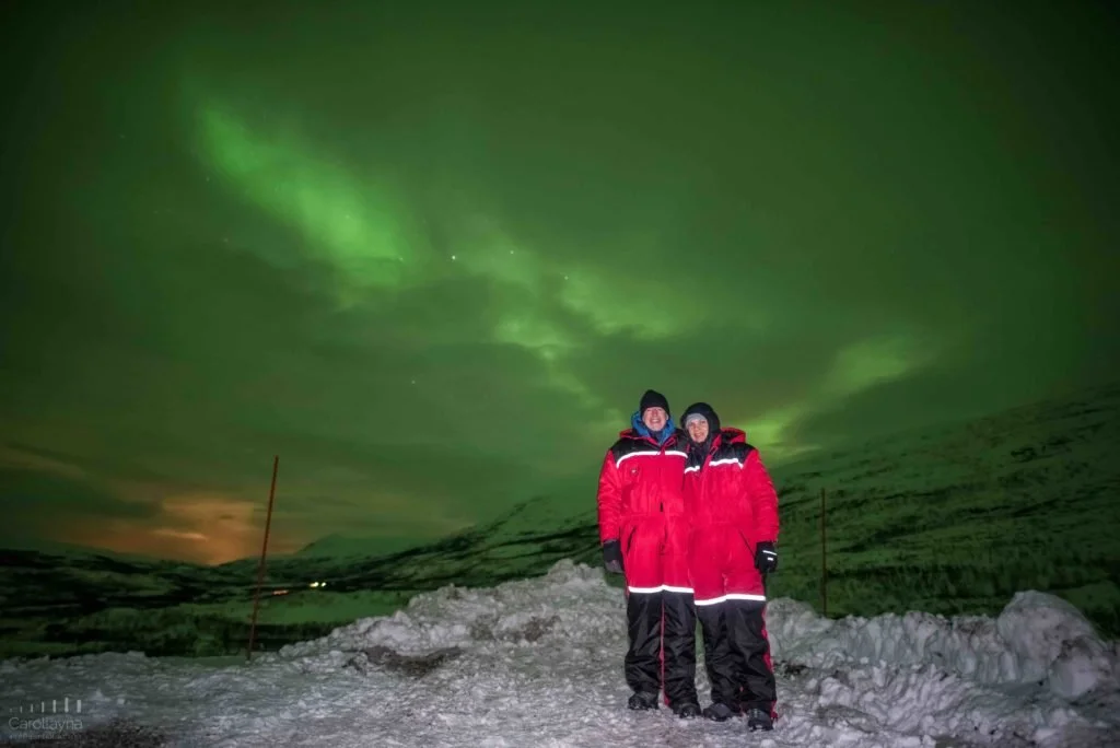 Emma and Trevor standing with green colours of the Northern Lights in the background