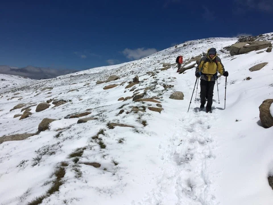 hikers descending Mt Kosciuszko on the Main Range Track which is covered in snow