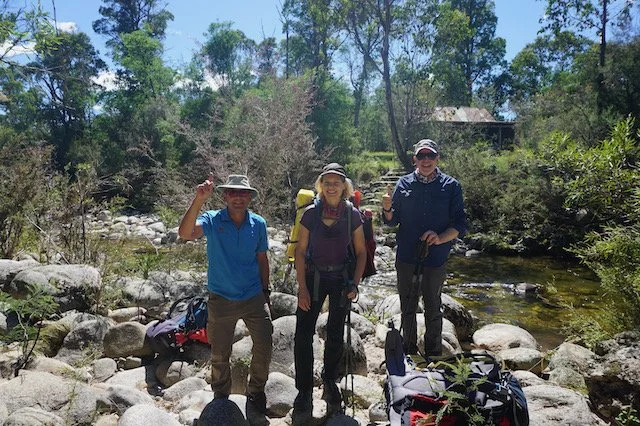 The three hardy hikers standing on rocks near the river