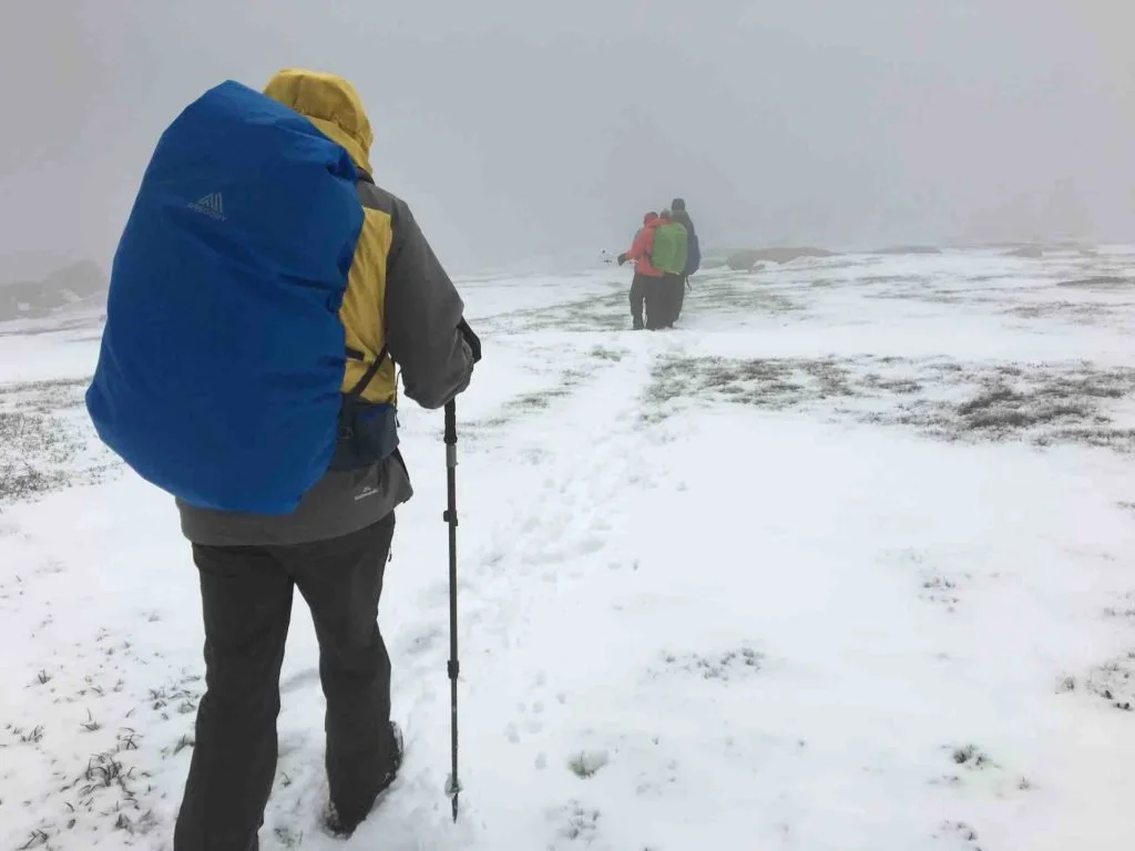 a hiker in rain gear setting off in the snow
