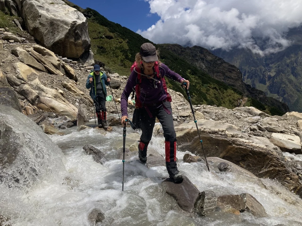 2 trekkers crossing fast flowing water