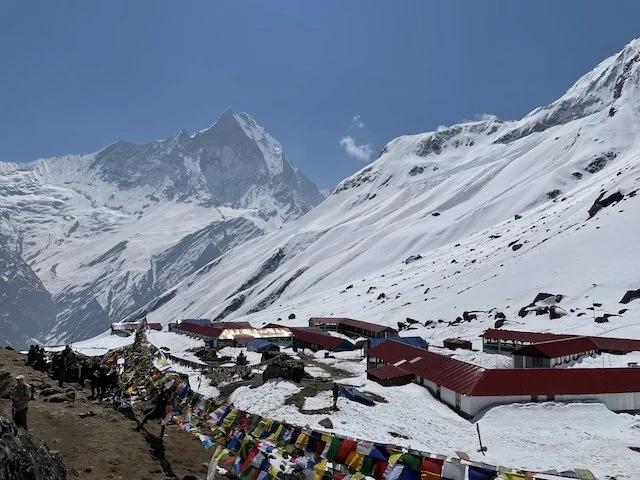 teahouses and lodges at Annapurna I south base camp, with prayer flags in foreground and the ground covered in snow