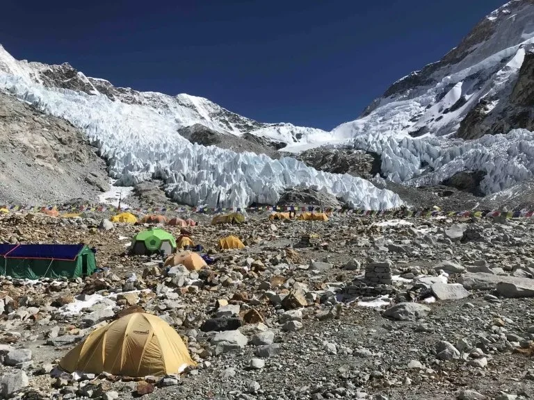 Makalu Advance Base Camp with many colourful tents on the rocks in front of the ice penitentes