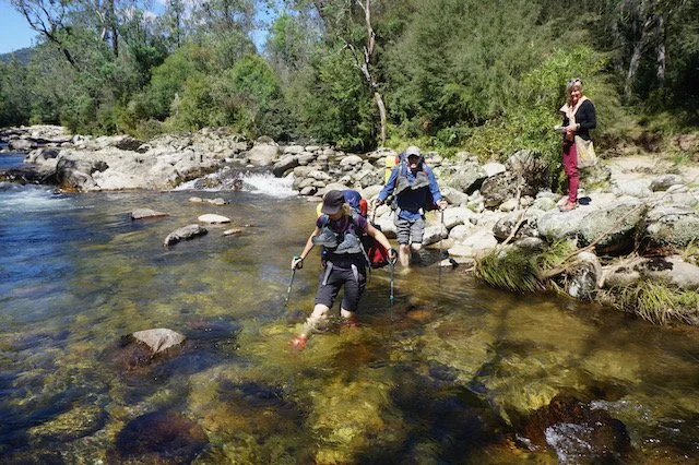 hikers wading through knee-deep water to cross the river at Geehi Flat