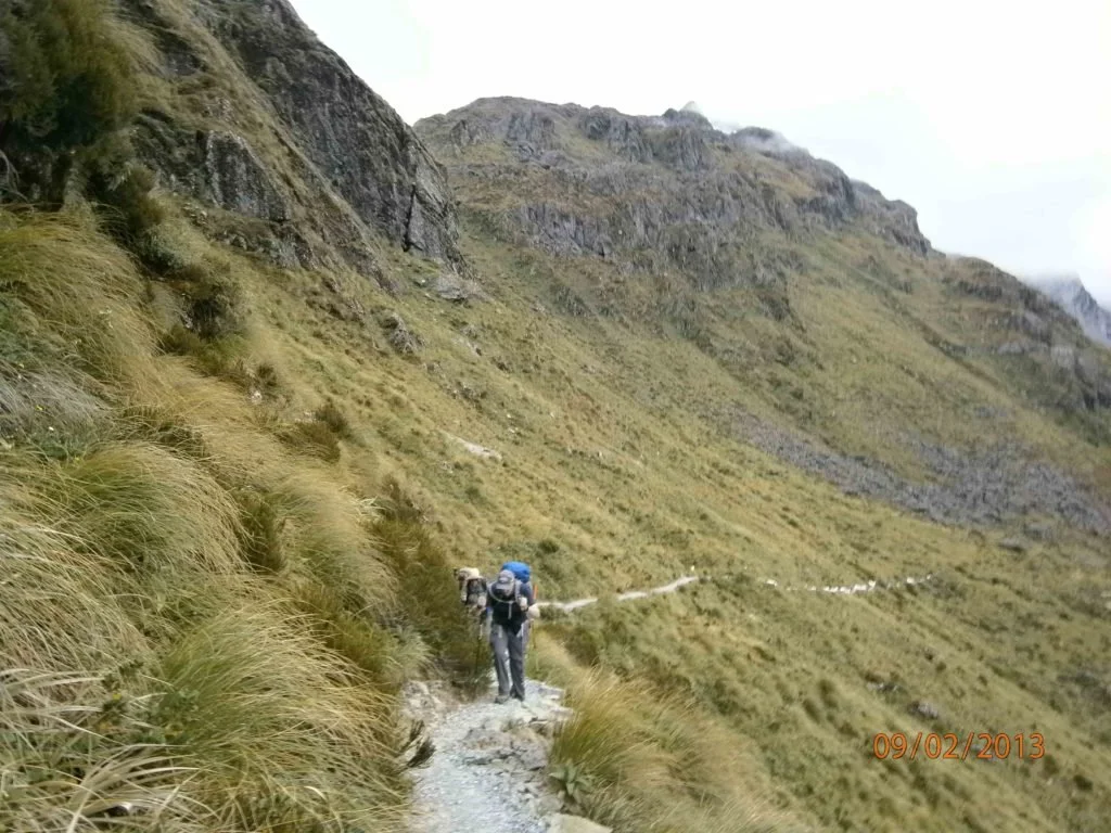 hikers walking along exposed trail on mountainside