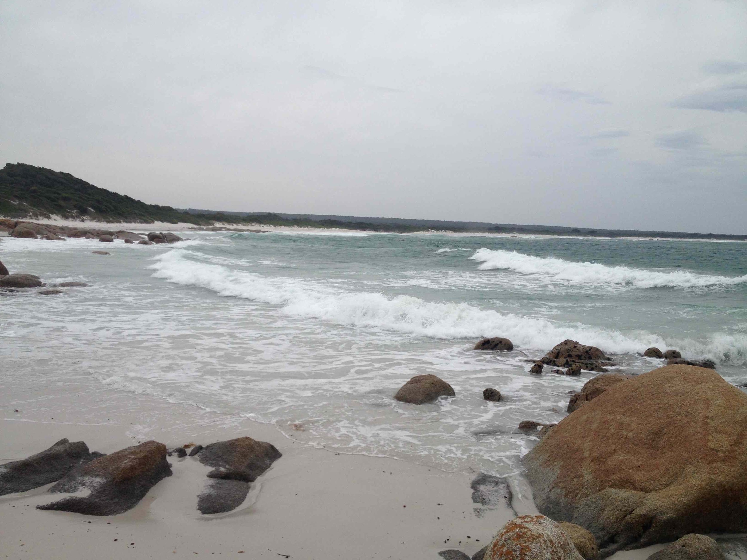 Moody beach scene with cloudy sky and waves rolling in