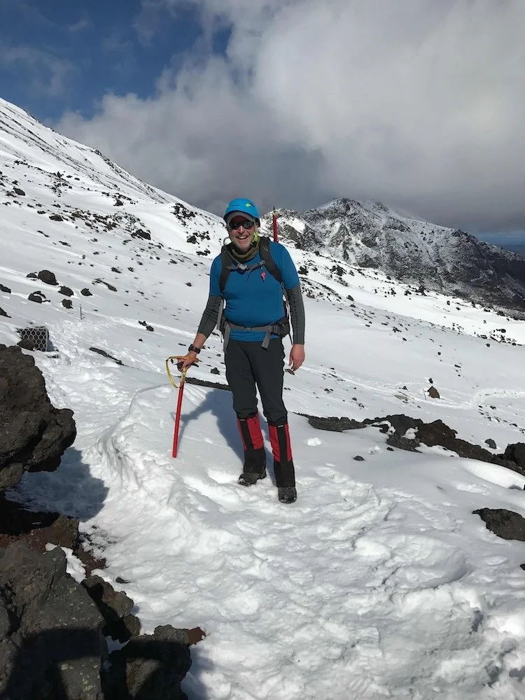 hiker with ice axe and helmet standing in the snow