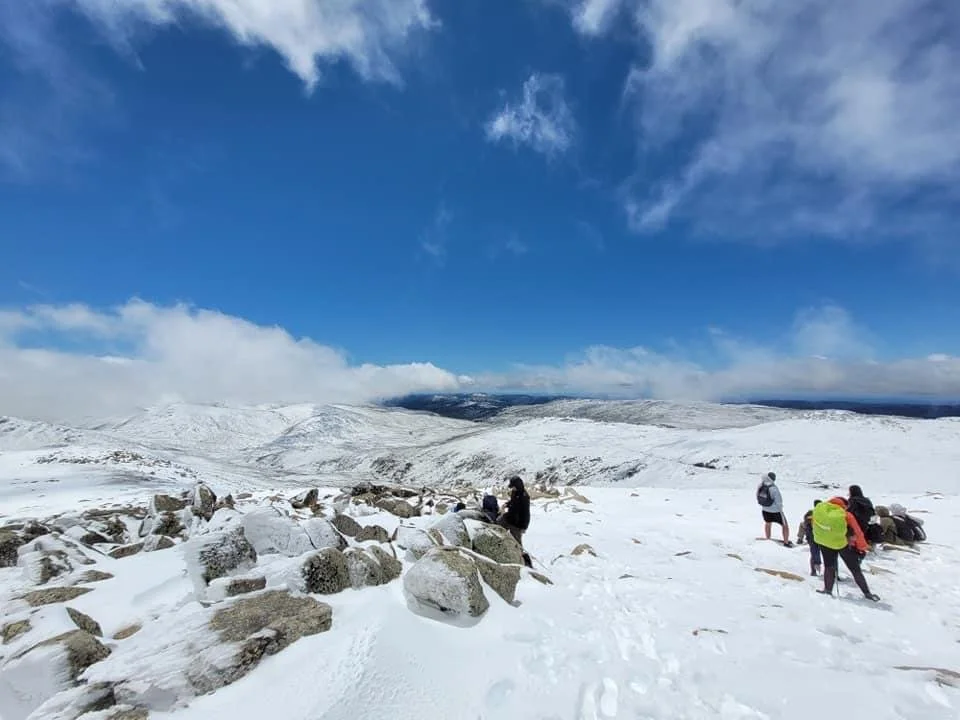 trekkers stopping for a break to view the snowy landscape under a bright blue sky